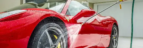 A person washing a red Ferrarri using Power Jet